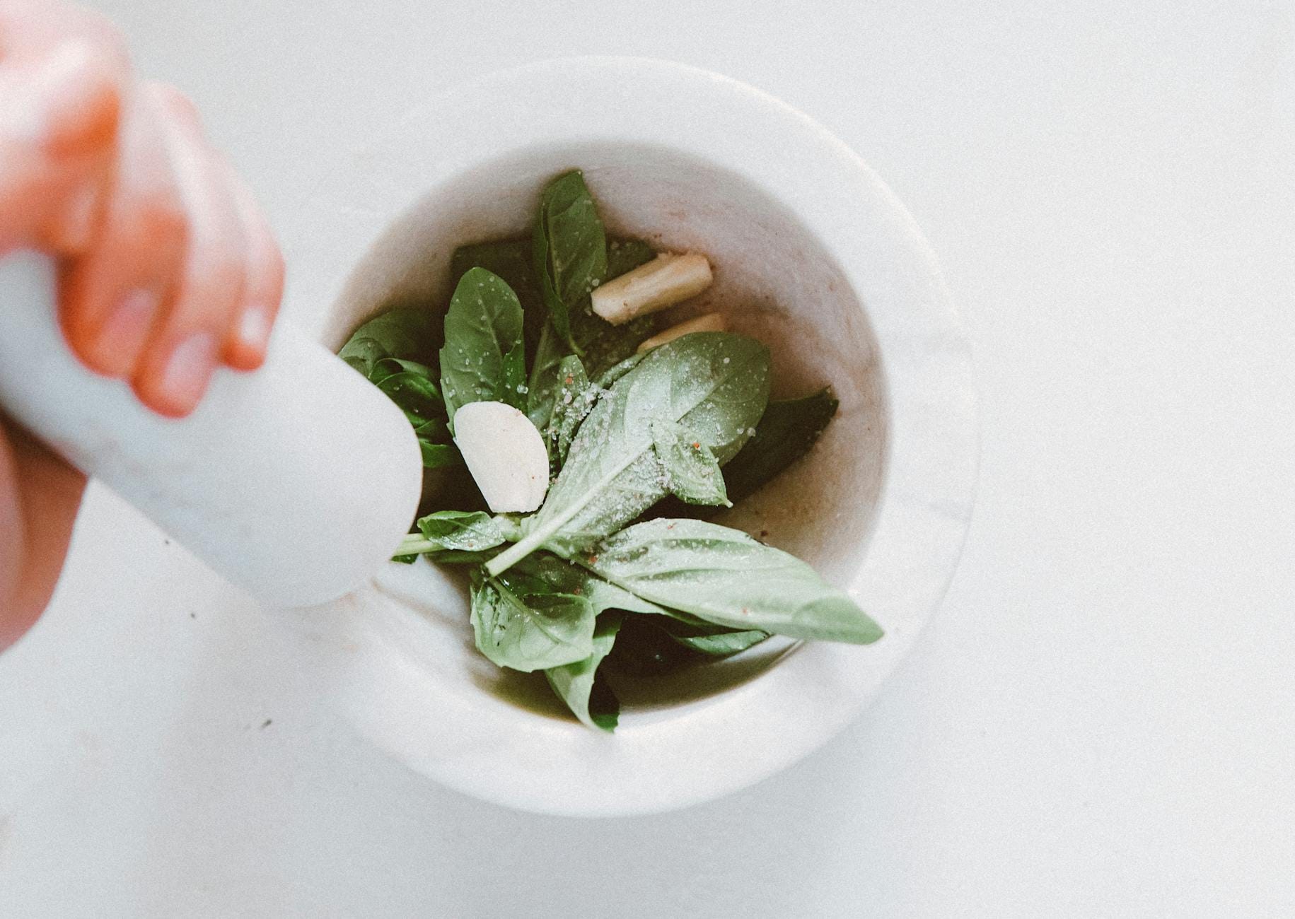 Bazyliowe liście ucierane w moździerzu na domowe pesto