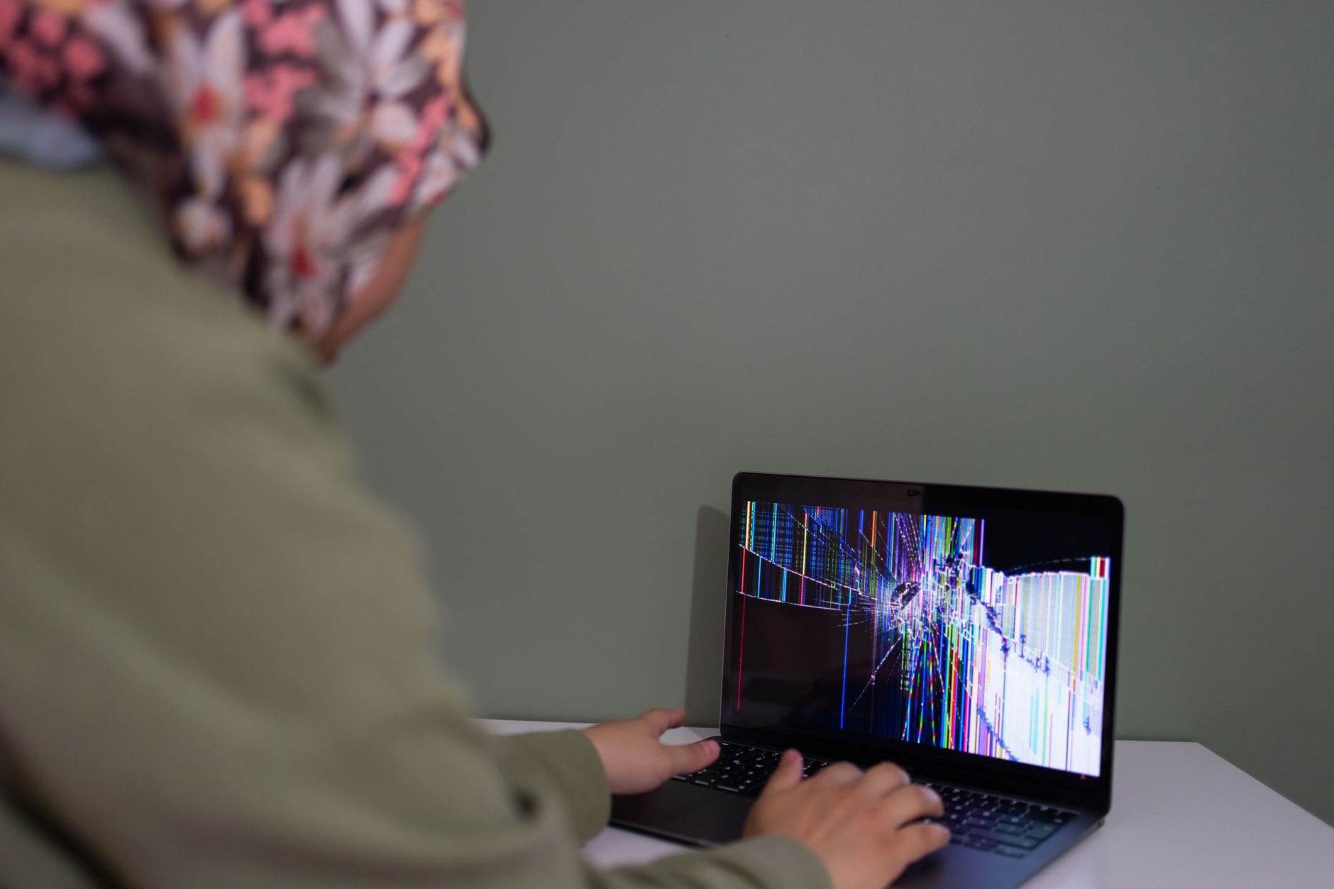 Osoba korzysta z laptopa z kolorowo popękanym ekranem