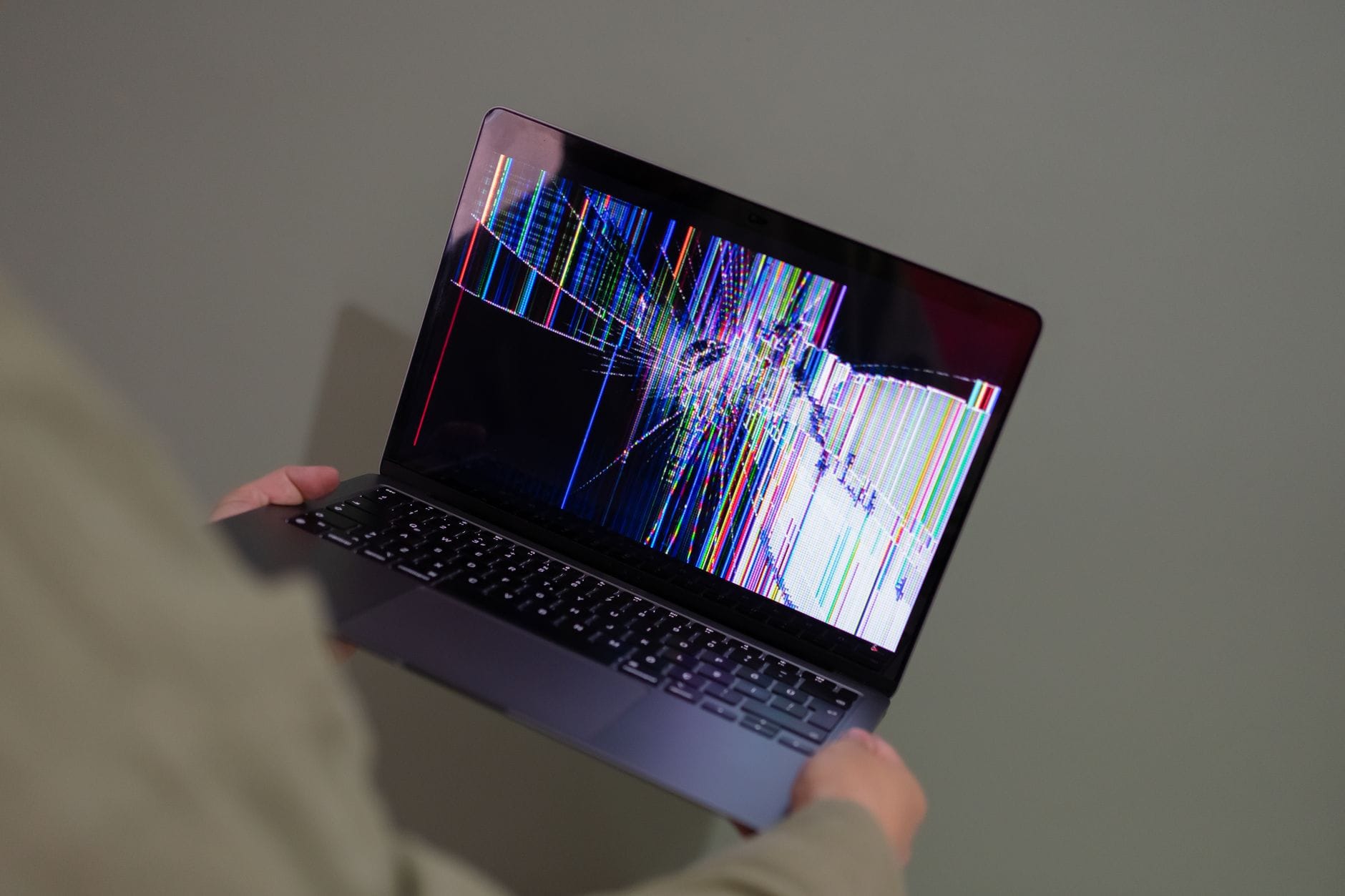 Osoba trzyma laptop Toshiba z kolorowymi zakłóceniami na uszkodzonej matrycy