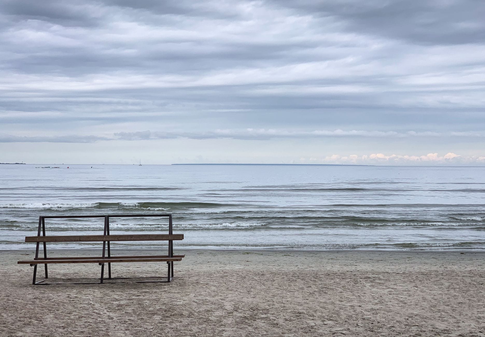 Pusta ławka nad Bałtykiem z widokiem na morze i pochmurne niebo