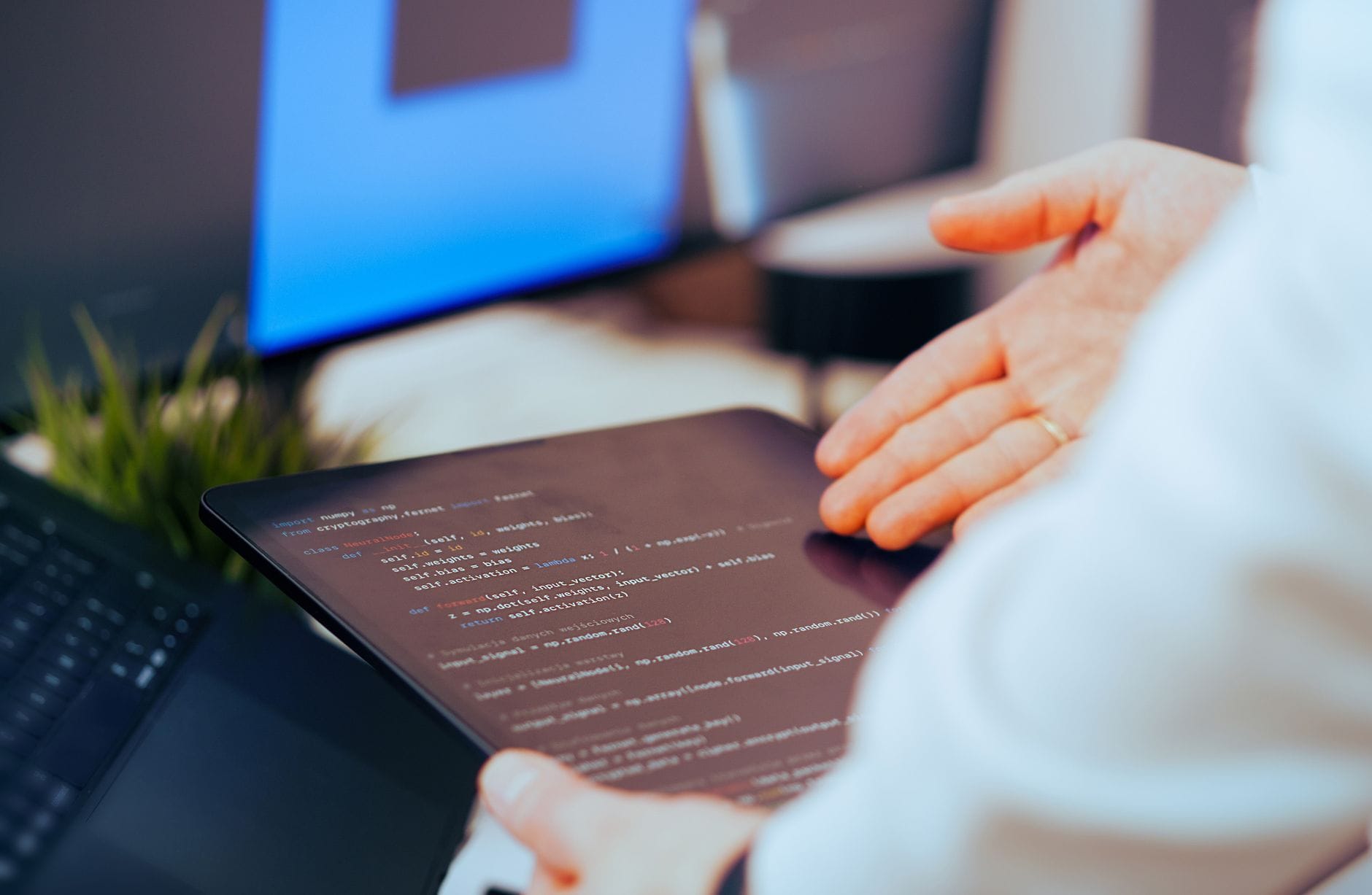 Bezpieczne korzystanie z AI w programowaniu: jak nie wkleić do czatu poufnego kodu produkcyjnego Programista analizuje kod na tablecie w nowoczesnym biurze