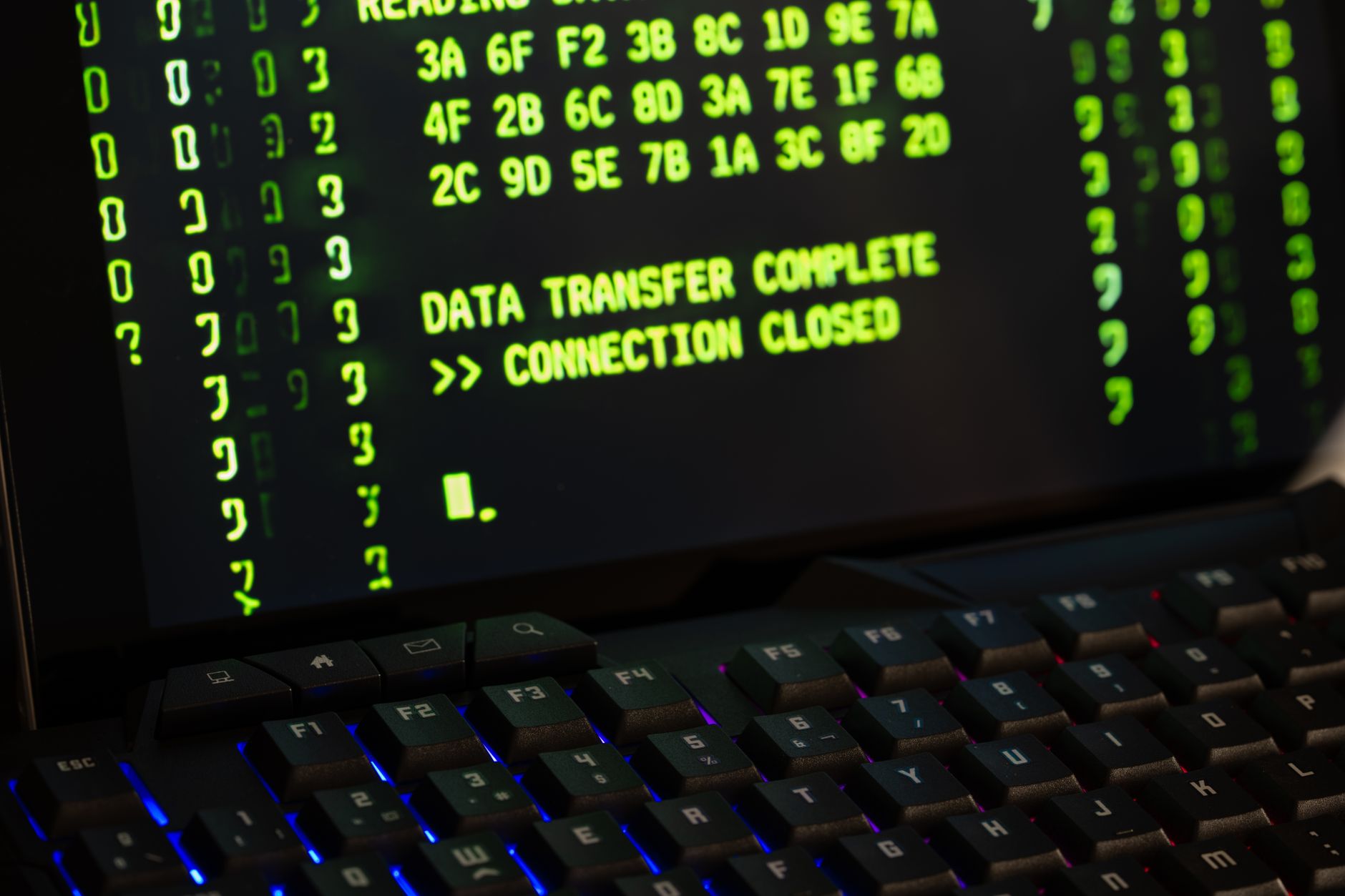 Monitor z komunikatem Data transfer complete i klawiaturą na biurku